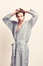Man with beard in blue dressing gown on grey background.