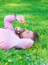 Man with beard on calm face sniffs dandelion. Peace and tranquility concept. Bearded man with daisy flowers in beard lay