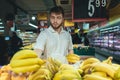 A man with a beard chooses bananas in the vegetable department of the supermarket.