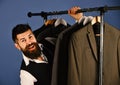 Man with beard by clothes rack. Businessman with excited face