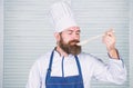 Man with beard in cook hat and apron hold cooking tools. Cooking as professional occupation. Hipster bearded chef hold Royalty Free Stock Photo