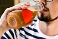 A man with a beard drinks kvass from a plastic transparent bottle. close-up. man holds a bottle with a drink