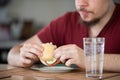 A man with a beard eats a sandwich at the table. Royalty Free Stock Photo