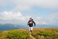 Man with beard enjoy freedom, runs on top of mountain. Hipster feels free while hiking, sky background. Hipster or Royalty Free Stock Photo