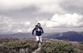 Man with beard enjoy freedom, runs on top of mountain. Hipster feels free while hiking, sky background. Hipster or Royalty Free Stock Photo