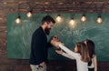 Man with beard in formal suit teaches schoolgirls physics. Teacher and girls pupils in classroom near chalkboard