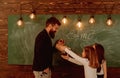 Man with beard in formal suit teaches schoolgirls physics. Teacher and girls pupils in classroom near chalkboard