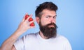 Man beard hipster strawberries between fingers blue background. Carbohydrate content strawberry. Strawberries safest