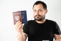 A man with a beard holding a passport of Russia and Ukraine translation: - Ukraine. Passport, Russian Federation Royalty Free Stock Photo