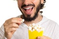 Bearded man is holding a popcorn in his hand. Bundle of popcorn