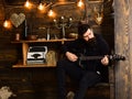 Man with beard holds black electric guitar. Guy in cozy warm atmosphere play music. Man bearded musician enjoy evening