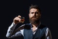 Man with beard holds glass brandy. Bearded drink cognac. Sommelier tastes drink. Man holding a glass of whisky. Sipping
