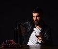 Man with beard holds glass of wine on dark brown background. Sommelier tastes expensive drink. Winetasting and Royalty Free Stock Photo