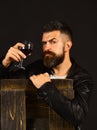 Man with beard holds glass of wine on dark brown background. Winetasting and degustation concept. Sommelier tastes