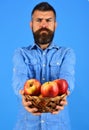 Man with beard holds wicker bowl with fruit