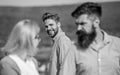 Man with beard jealous aggressive because girlfriend interested in handsome passerby. Jealous concept. Passerby smiling Royalty Free Stock Photo