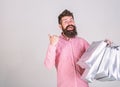 Man with beard and mustache carries bunch of shopping bags, grey background. Guy shopping on sales season, pointing at Royalty Free Stock Photo