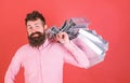 Man with beard and mustache carries shopping bags on shoulder, red background. Hipster on cool face is shopping addicted Royalty Free Stock Photo