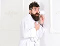 Man with beard and mustache eavesdrops using cup near wall. Hipster in bathrobe on surprised face secretly listen Royalty Free Stock Photo