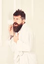 Man with beard and mustache eavesdrops using mug near wall. Hipster in bathrobe on concentrated face secretly listen Royalty Free Stock Photo