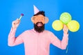 Man with beard and mustache on happy face holds air balloons, blue background. Party concept. Hipster in giant