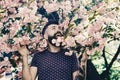 Bearded man with bloom of sakura tree on background. Hipster with sakura blossom in beard. Springtime concept. Man with