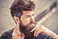 Man with beard and mustache looks thoughtful or troubled Bearded man on concentrated face touches beard. Hipster with Royalty Free Stock Photo