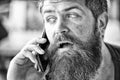 Man with beard and mustache mobile phone conversation defocused background. Bearded man hold mobile phone. Hipster Royalty Free Stock Photo