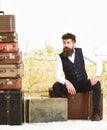 Man with beard and mustache packed luggage, white interior background. Luggage and relocation concept. Macho elegant on