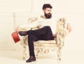 Man with beard and mustache sits on armchair, holds book, white wall background. Connoisseur on thoughtful face finished Royalty Free Stock Photo