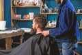 Man with beard and mustache sits in barbershop, beauty supplies on background. Barbershop concept. Man bearded client of