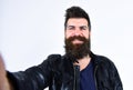 Man with beard and mustache on smiling face looking at camera. Macho wears leather jacket, white background. Hipster Royalty Free Stock Photo