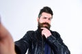 Man with beard and mustache on strict face looking at camera. Macho wears leather jacket, white background. Masculinity Royalty Free Stock Photo