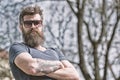 Man with beard and mustache on strict face, nature background, defocused. Bearded man wears modern sunglasses. Hipster Royalty Free Stock Photo