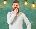 Man with beard and mustache on thoughtful face stand in front of chalkboard. Intellectual task concept. Guy thinking Royalty Free Stock Photo