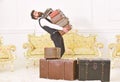 Man with beard and mustache wearing classic suit delivers luggage, luxury white interior background. Macho, elegant