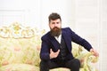 Man with beard and mustache wearing classic suit, sits on old fashioned armchair or sofa. Speaker, wise lecturer concept