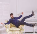 Man with beard and mustache wearing fashionable classic suit, sits, jumps on old fashioned armchair. Macho attractive Royalty Free Stock Photo