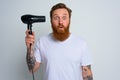 Amazed man with beard play with hair dryeras a handgun