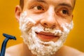 Man with a beard shaves with foam and a loom. Closeup portrait. Self care concept