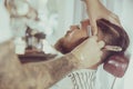 Man with a beard is shaving with a razor in a barbershop