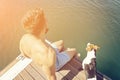 The man with a beard sits on the edge of the pier with a dog Royalty Free Stock Photo