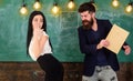 Man with beard slapping student, chalkboard on background. Girl on helpless face punished by teacher. Schoolmaster