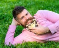 Man with beard on smiling face enjoy nature. Bearded man with daisy flowers lay on meadow, lean on hand, grass Royalty Free Stock Photo