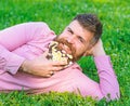 Man with beard on smiling face enjoy nature. Bearded man with daisy flowers lay on meadow, lean on hand, grass