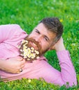 Man with beard on smiling face enjoy nature. Bearded man with daisy flowers lay on meadow, lean on hand, grass Royalty Free Stock Photo