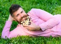 Man with beard on smiling face enjoy nature. Masculinity concept. Bearded man with daisy flowers lay on meadow, lean on Royalty Free Stock Photo