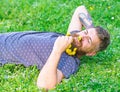 Man with beard on smiling face enjoy spring. Bearded man with dandelion flowers in beard lay on meadow, grass background Royalty Free Stock Photo