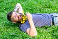 Man with beard on smiling face enjoy spring. Bearded man with dandelion flowers in beard lay on meadow, grass background Royalty Free Stock Photo