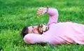 Man with beard on smiling face sniffs dandelion. Macho with daisies in beard relaxing. Bearded man with daisy flowers in